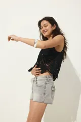 Shorts mini de denim gris con cintura clásica y cierre con botón. Modelo con bolsillos delanteros, bolsillos atrás con solapa y botón, bolsillo monedero y bajo sin rematar.