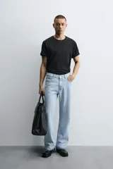 Pantalón de jean celeste de corte flare, con tiro medio, cinco bolsillos, cierre frontal con cremallera y botón, y bajo con acabado irregular.