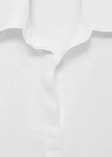 Camisa blanca oversize de lino, con cuello camisero, manga larga con puños abotonados y cierre frontal con botones.