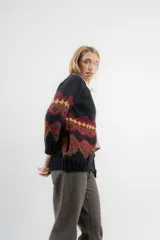 Saco de lana y poliamida color negro con diseño geométrico en tonos marrón, rojo y amarillo. Tiene silueta recta, largo debajo de la cola, bolsillos en los costados y escote polera con botones en todo el largo.