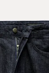 Pantalón de jean negro con corte recto, tiro medio, cinco bolsillos y detalle de banda lateral a contraste en color negro más oscuro.