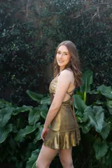 Vestido corto de lentejuelas color verde oliva, con escote en V, breteles finos cruzados en la espalda, cut-outs laterales y volado en el ruedo.