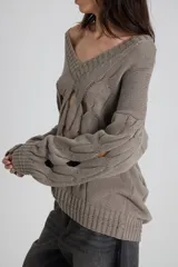 Sweater tejido de color negro con diseño de cortes en el pecho y mangas largas.