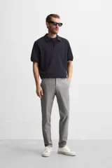Pantalón negro de corte slim fit, confeccionado en tejido elástico. Cuenta con cintura elástica, bolsillos frontales y traseros de vivo. Cierre frontal con cremallera y botón.