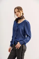 Camisa azul de tencel con calce entallado, cuello redondo, mangas largas con frunces en los hombros y costuras a contratono.
