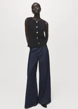 Chaleco negro de tejido de punto fino, con cuello caja, diseño recto y cierre frontal de botones dorados.