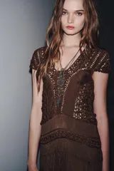 Vestido largo color marrón con detalle de crochet en el corpiño, escote redondo y manga corta. Cierre en la espalda con lazadas.