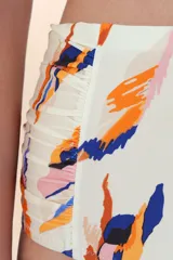 Calzón de bikini tiro alto, color blanco roto, con estampado abstracto en tonos naranja, azul y rosado. Presenta frunces decorativos en los laterales.