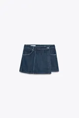 Falda pantalón corta de tiro alto confeccionada en denim azul oscuro. Presenta bolsillos delanteros y traseros de parche. El cierre es cruzado con cremallera oculta y botón metálico.