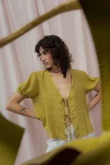 Blusa blanca de lino con escote en V, mangas cortas abullonadas y cierre frontal con lazos.