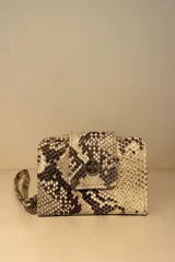 Billetera pequeña con estampado de piel de cocodrilo en tonos beige y marrón. Cierre con broche a presión y correa de muñeca.