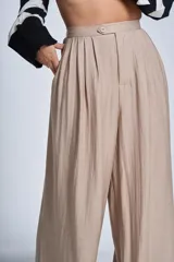 Pantalón de vestir color beige, de corte palazzo, con cintura alta, pinzas delanteras y elástico en la parte trasera de la cintura.