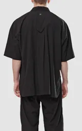Camisa negra de manga corta con doble bolsillo ojal en delantero, realizada en tejido plano y silueta oversize.