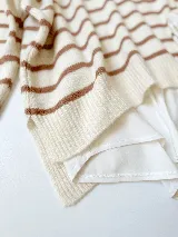 Sweater tejido color marrón con rayas horizontales blancas, cuello redondo y corte holgado.