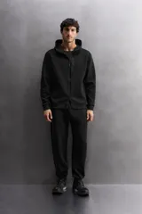 Pantalón jogger color marrón oscuro, corte regular fit, confeccionado en tejido técnico compacto de algodón con elasticidad. Cuenta con cintura elástica ajustable con cordón, bolsillos frontales y bolsillo lateral con cierre de cremallera.