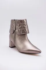 Botas cortas color peltre con taco cuadrado, capellada de cuero y cuello con diseño capitoné y apliques brillantes.