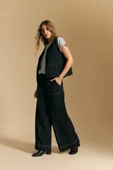 Pantalón ancho de tiro alto, color negro, con costuras contrastantes en blanco que definen los bolsillos y los bordes.