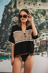 Remera de tejido calado color crudo con rayas horizontales rojas y terminaciones marrones, con cierre frontal y logo bordado.