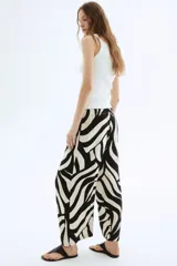 Pantalón tobillero de viscosa con estampado abstracto en blanco y negro, tiro alto con elástico en la cintura, bolsillos laterales y piernas amplias rectas.