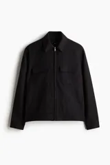 Campera camisera negra de corte recto, con cuello clásico, cierre frontal con cremallera, dos bolsillos de parche con solapa en el pecho y bolsillos laterales.