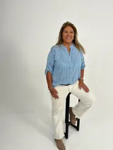 Camisa celeste a rayas verticales blancas, con cuello mao y mangas 3/4 con botón.