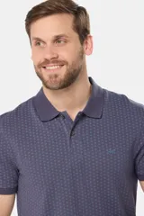 Polo de piqué color azul oscuro con un mini estampado geométrico repetitivo en todo el cuerpo. Presenta cuello y tapeta de botones en color liso, y un pequeño logo bordado en el pecho.