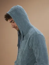 Campera con capucha de toalla de algodón color verde azulado, con cierre frontal y bolsillos laterales.