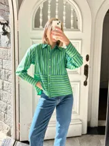 Camisa verde con rayas verticales azules, de corte recto y manga larga.