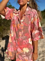 Camisa oversize de manga corta con estampado floral en tonos rosados, naranjas y crema. Confeccionada en una mezcla de lino y viscosa, presenta cuello camisero y cierre frontal con botones.