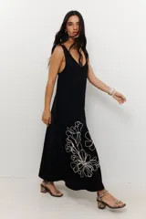 Vestido largo de tirantes color azul con estampado floral blanco en el lateral inferior.