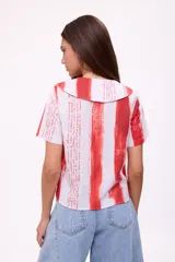 Blusa de manga corta con cuello camisero y botones, con estampado de rayas verticales rojas y texto manuscrito.