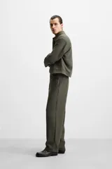Pantalón largo color verde oscuro, de corte recto y tiro medio. Confeccionado en tejido con viscosa, con cintura elástica, bolsillos laterales y trasero de vivo. Cierre frontal con cremallera y botón.