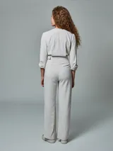 Mono largo color crudo, de lino, con cuello tipo blazer, mangas 3/4 con puños arremangados, cinturón con hebilla forrada y pantalón de corte recto.