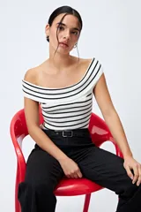 Top tejido blanco con rayas horizontales negras, escote bardot y trama acanalada.