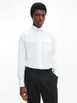 Camisa blanca de poplin con corte relaxed, mangas largas, cierre frontal con botones y bolsillo con solapa.