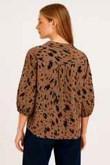 Blusa con estampado abstracto en tonos beige y negro, escote en V y mangas 3/4.