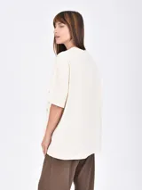 Remera blanca de corte holgado con cuello en V y estampado frontal con la frase 'Los Angeles' y el número '97' en color bordó.