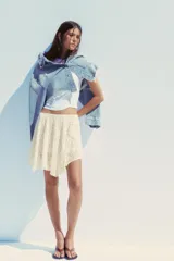Falda corta de encaje color crema con forro interior. Presenta cintura elástica y bajo asimétrico con terminación en picos.