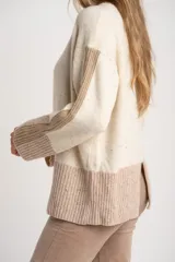 Sweater de lana color crema con efecto tweed, de calce oversize y cuello redondo. Presenta bloques de color en la parte inferior, puños y laterales de las mangas en tono beige con textura acanalada y detalles brillantes.