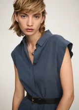 Vestido camisero midi color beige, sin mangas, con cuello camisero, cinturón ajustable y aberturas laterales.