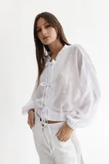 Camisa blanca de voile de algodón con cuello a la base y mangas balloon. Cierre frontal con lazos.