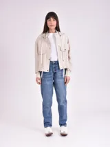 Chaqueta color crudo con capucha, cierre con botones a presión, bolsillos delanteros con solapa y cordón ajustable en la cintura.