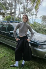 Bermuda negra unisex de felpa con pretina elástica ajustable, tiro alto, bolsillos laterales y un bolsillo trasero ojal. Presenta un pliegue delantero de gran tamaño.