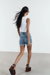 Bermuda de jean celeste, corte mom fit, tiro alto, con cinco bolsillos y ruedo doblado.