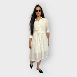 Vestido camisero midi negro con cuello clásico, mangas 3/4 y falda acampanada. Presenta un cinturón de lazo en la cintura y cierre frontal con botones.