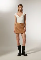 Minifalda color marrón de poliéster con cierre frontal de cremallera y apliques de tachas metálicas formando estrellas. 