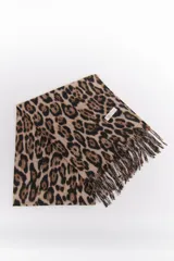 Bufanda rectangular de tejido suave color beige con estampado de leopardo en marrón y negro. Tiene flecos cortos en los extremos.