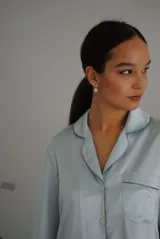 Pijama de satén celeste con vivos en contraste. Incluye camisa de manga larga con botones y pantalón recto con elástico y lazo en la cintura.