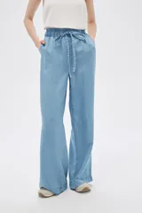 Pantalón de jean celeste, de corte ancho, con cintura elástica y cordón ajustable.