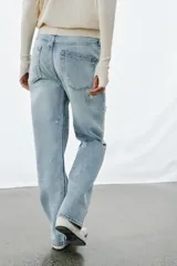 Jeans de tiro bajo, corte recto y largo completo, con efecto lavado y detalles de rotos en el delantero. Cierre frontal con cremallera y botón, y diseño de cinco bolsillos.